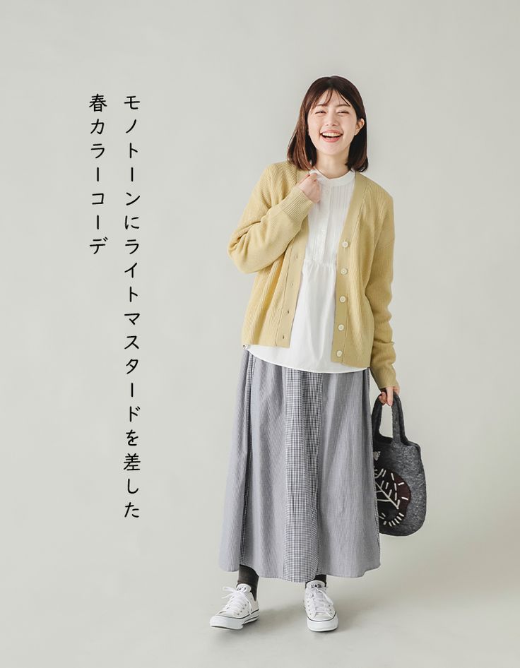 Ținută quiet layering: cardigan galben-muștar peste bluză albă, fustă gri plisată și teniși albi